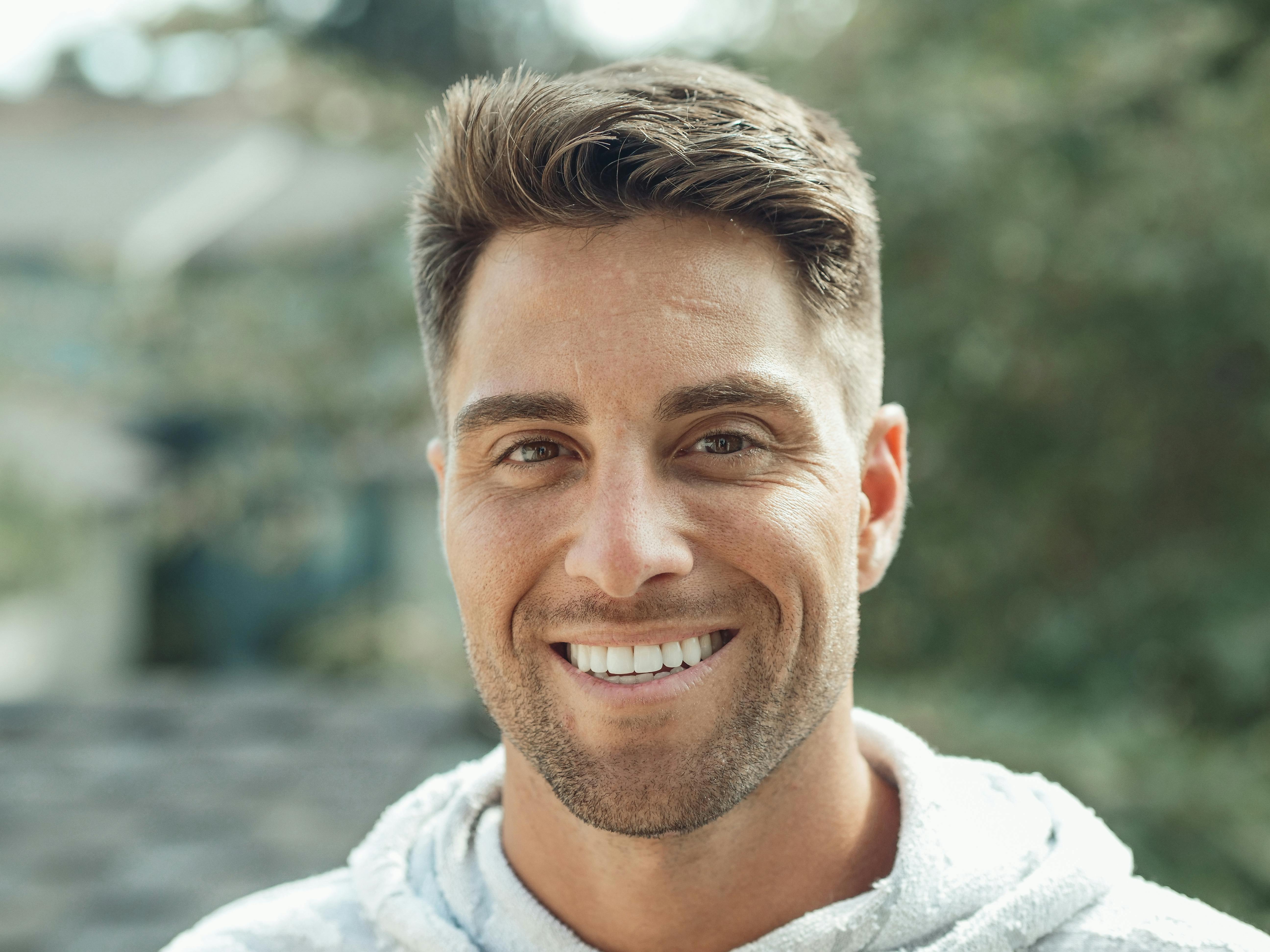 Man with a beard and short hair smiling outdoors